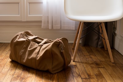 白色和棕色木椅旁的棕色行李包
